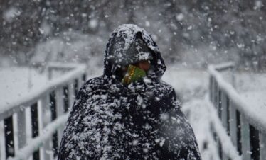There is snow all around and a man is shivering in the snow in Kashmir, in Kashmir tour package