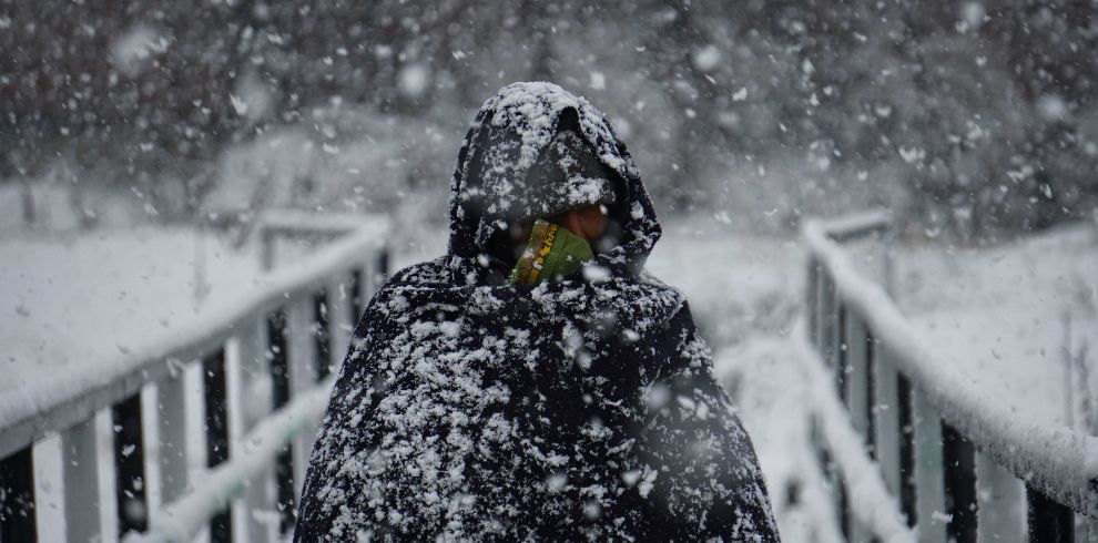 There is snow all around and a man is shivering in the snow in Kashmir, in Kashmir tour package